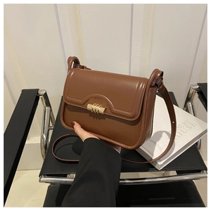 Detail of premium brown leather shoulder bag with elegant golden twist-lock buckle