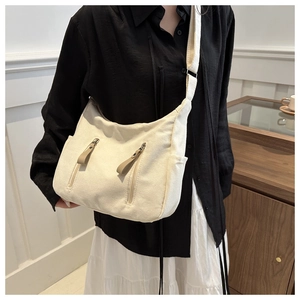 Detail of cream canvas bag featuring dual front zipper pockets and side compartments