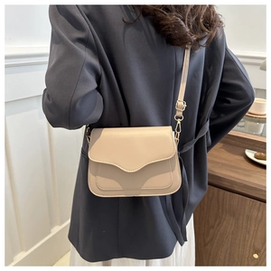 Beige faux leather crossbody bag with adjustable strap and flap shown on model