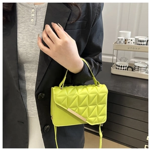 Detailed shot of neon yellow quilted handbag with geometric patterns and gold metal bar
