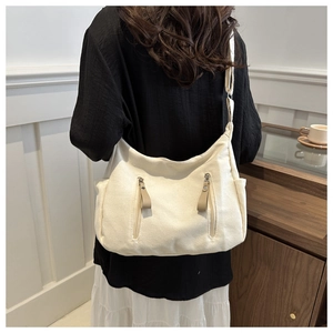 Detail view of large canvas tote bag showing vertical zippers and side pocket on model