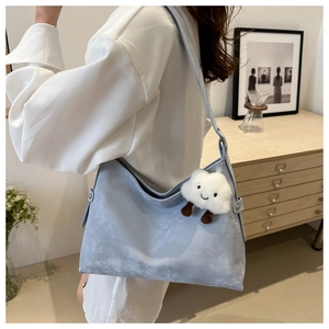 Detail of light blue vintage hobo bag with cloud plush pendant and metal rivet accents