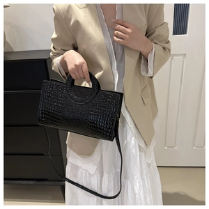 Detail view of black crocodile pattern shoulder bag with distinctive round handle