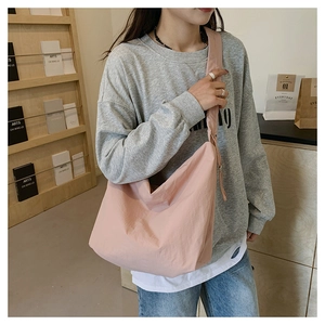 Detailed view of pink nylon crossbody bag with casual tied strap on a female model