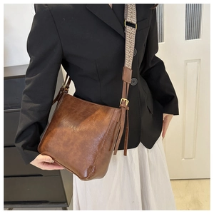 Detailed view of brown retro bucket bag with decorative geometric woven shoulder strap