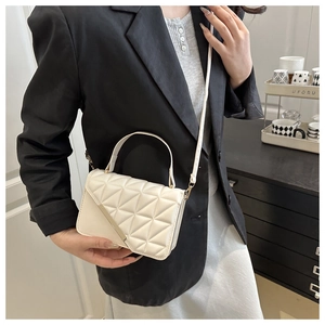 Detail view of white quilted crossbody bag with minimalist metal trim and leather strap