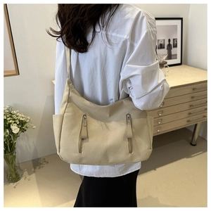 Detail of beige canvas tote bag with functional zippers and side pockets in daily use