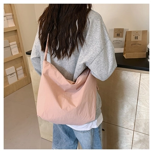 Close-up of lightweight pink nylon tote bag with pleated texture and wide shoulder strap