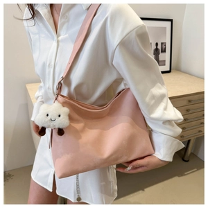 Detail of light pink hobo bag with plush cloud charm and metal chain decoration