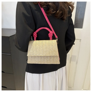 Detail of hand-woven straw crossbody bag featuring pink knotted handles and slim shoulder strap