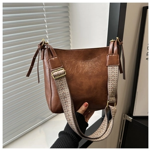 Close-up of vintage brown bucket bag with decorative ethnic weave shoulder strap