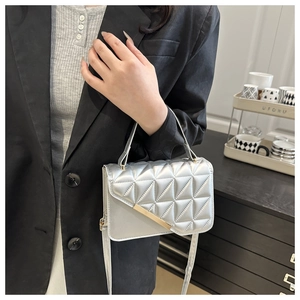 Detail of silver quilted crossbody bag with golden metal trim and sleek PU texture