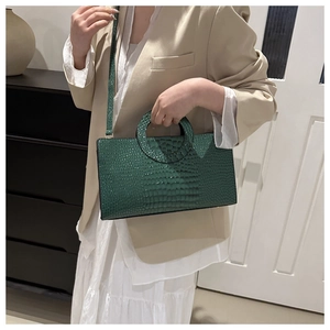 Dark green croc-effect handbag with circular cut-out handle on a beige blazer outfit