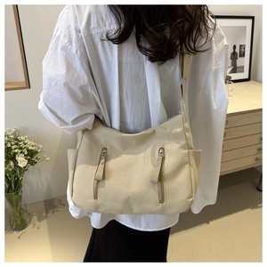 Close-up of beige canvas shoulder bag featuring vertical zipper pockets and side slots