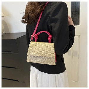Detail of woven straw handbag featuring hot pink leather handle and adjustable shoulder strap