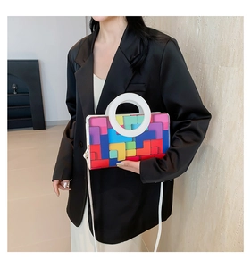 Detail of colorful geometric pattern handbag with white circular handle and leather strap