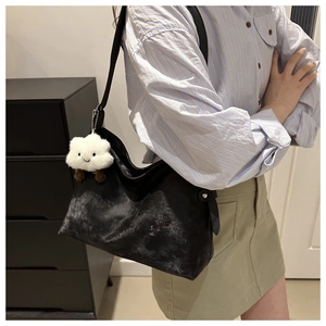 Detail of vintage black bucket bag featuring textured finish and white cloud charm