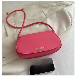 Close-up of pink mini saddle bag with silver Fashion logo and thin shoulder strap