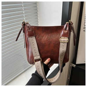 Detail of vintage brown bucket bag featuring a bohemian style woven shoulder strap