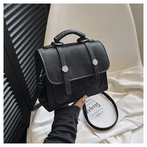 Detail of a black crossbody bag featuring silver metal buckles and matte leather texture