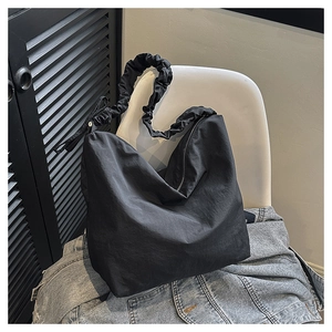 Minimalist black nylon crossbody bag featuring stylish ruched straps and a soft tote shape