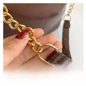 Detalle de la correa de cuero marrón con anillos de cadena dorados y costuras de calidad