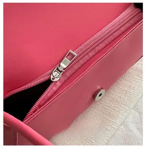 Close-up of smooth metal zipper and magnetic buckle on pink leather saddle bag