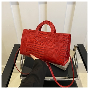 Detail of red crocodile embossed faux leather handbag with unique circular cutout handle