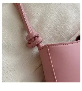 Detail of pink leather handbag showing knotted shoulder strap and white contrast stitching