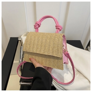 Detail of hand-woven straw crossbody bag featuring pink knotted handles and texture