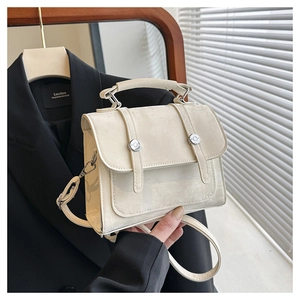Detail view of cream white flap handbag with silver metallic buckles and top handle