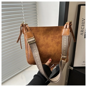 Detail of vintage brown PU leather bucket bag with wide colorful geometric woven strap