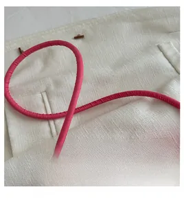 Detail of comfortable pink round handle and neat stitching on a minimalist shoulder bag