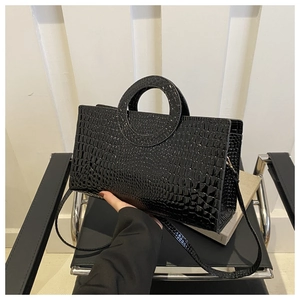 Close-up of black glossy crocodile pattern texture and hollow circular handle detail