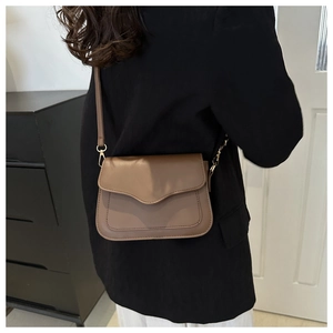 Close-up of brown crossbody bag with scalloped flap and gold-tone metal hardware