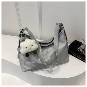 Detail of silver metallic hobo tote bag with a cute white cloud pendant on the strap