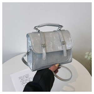 Detail of silver metallic textured crossbody bag with flap and metal buckle decorations