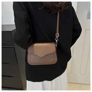 Detail of tan synthetic leather crossbody bag showing stitching and golden hardware