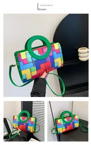 Detail view of colorful geometric block pattern and green round handle on a chic crossbody bag