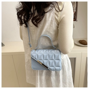 Detail of light blue crossbody bag with triangle quilting and gold metal trim