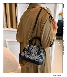 Detail of vintage shell cross-body bag with floral patterns and gold metal zippers