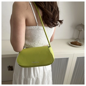 Detail of avocado green PU leather shoulder bag with Fashion logo shown on a model