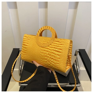 Close-up of bright yellow croc-effect handbag with unique circular cutout handles