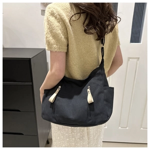 Detailed view of black canvas hobo bag with zip pockets and adjustable strap on model