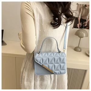 Detail of light blue quilted crossbody bag with gold metal trim on elegant lady