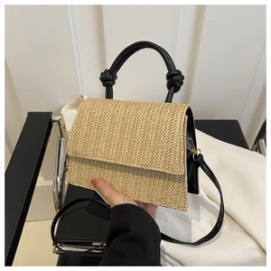 Detail of woven straw handbag with black leather knot handle and contrast stitching