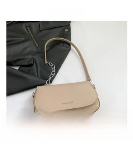 Detail view of beige crossbody bag with silver metal chain strap and flap closure