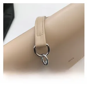 Detailed close-up of leather shoulder strap with silver D-ring and metal chain links