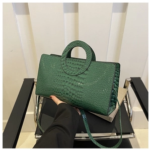 Detail of emerald green crocodile-patterned PU leather bag with unique round cutout handle