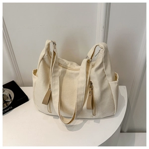 Detail of cream canvas tote bag showing side pockets and premium woven texture